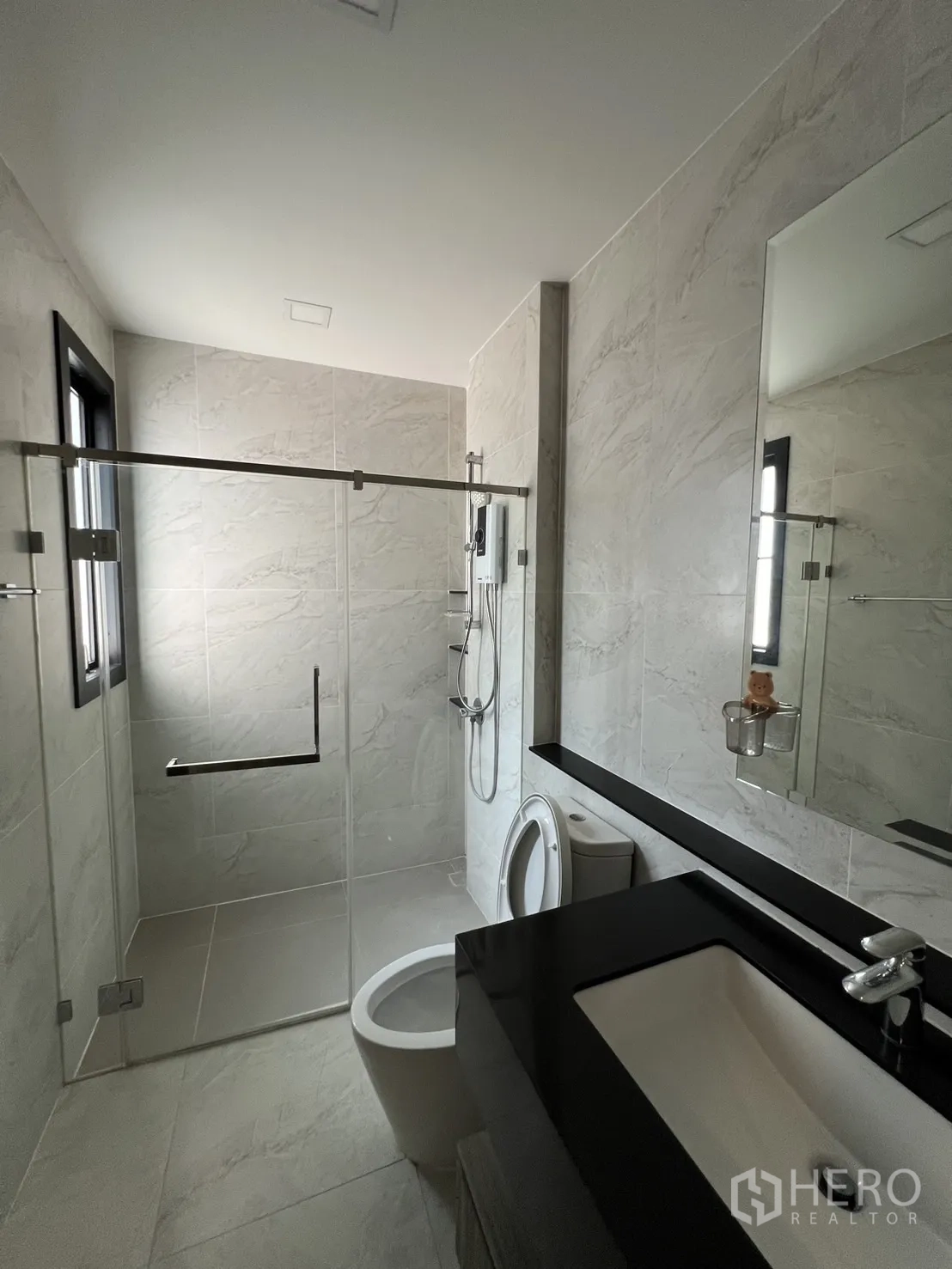 Detached House for rent or sale in Prawet, Bangkok - Modern bathroom with gray tiles and glass shower enclosure.