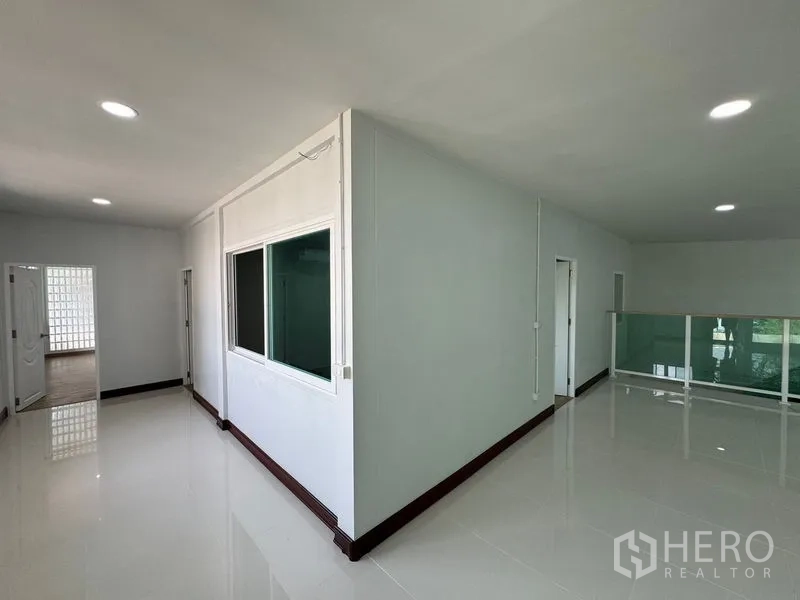 Home Office for rent in Bueng Kum, Bangkok - Upper landing with glossy tiles and a glass balustrade beside rooms.