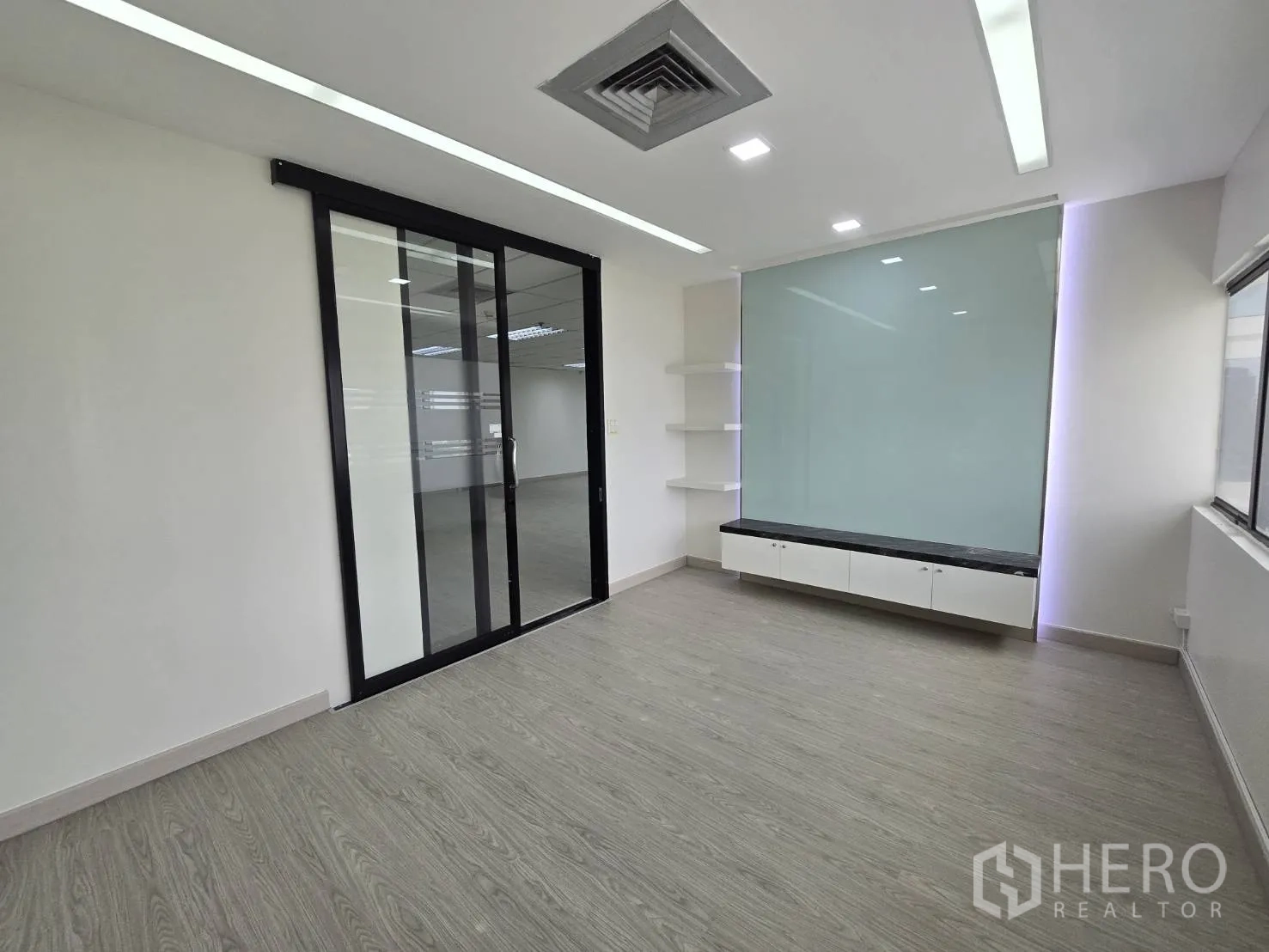 Office Space for rent in Khlong Toei, Bangkok - Compact office room with glass feature wall, built-in cabinet, and recessed lighting.