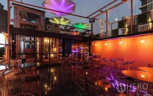 พื้นที่ขายปลีก ให้เช่า - ระเบียงรูฟท็อปแบบโอเพ่นแอร์ เก้าอี้ลวด กระจกบานใหญ่ และร่มดีไซน์สีสันยามเย็น