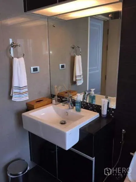 Condominium for rent in Khlong Toei, Bangkok - Modern vanity with square sink, mirror and storage in the bathroom.