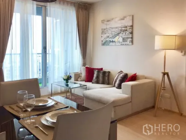 公寓 出租在Khlong Toei, Bangkok - 明亮客厅，转角沙发、餐桌与落地窗，连接阳台观城市景观。