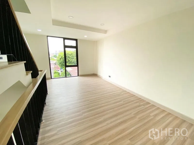 带办公室的家 出租或出售在Bang Na, Bangkok - 楼上房间，木地板与楼梯相邻，尽端设高窗。