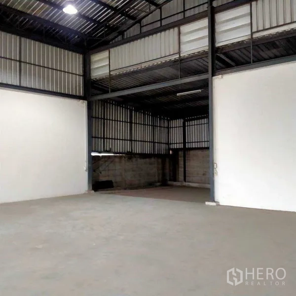 Warehouse for rent in Mueang Samut Sakhon, Samut Sakhon - High-ceiling storage hall with steel frame and partitioned section at the rear.