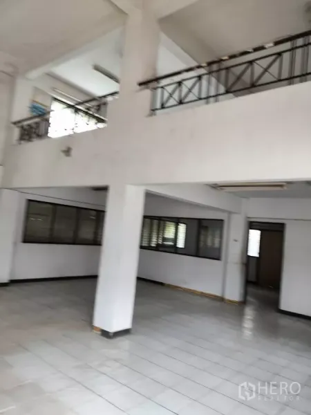 Shophouse for rent in Bueng Kum, Bangkok - Double-height shophouse interior with tiled floor, columns and mezzanine railings.