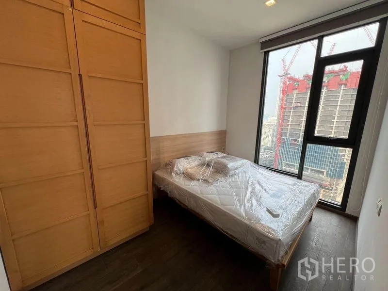 คอนโด ให้เช่าในRatchathewi, Bangkok - ห้องนอนรองพร้อมตู้เสื้อไม้และหน้าต่างชมเมือง เห็นอาคารก่อสร้าง