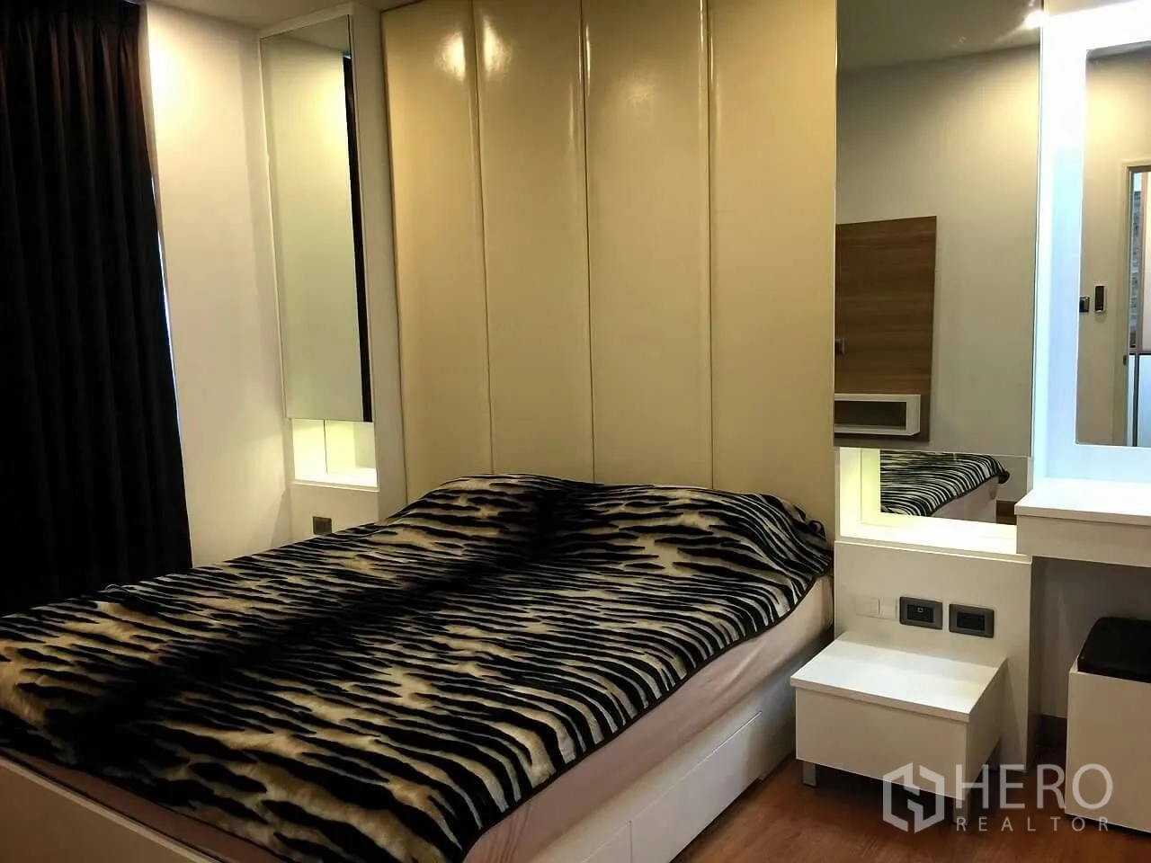 Condominium for sale in Huai Khwang, Bangkok - Cozy bedroom with upholstered headboard, mirrored panels and a bright dressing table.