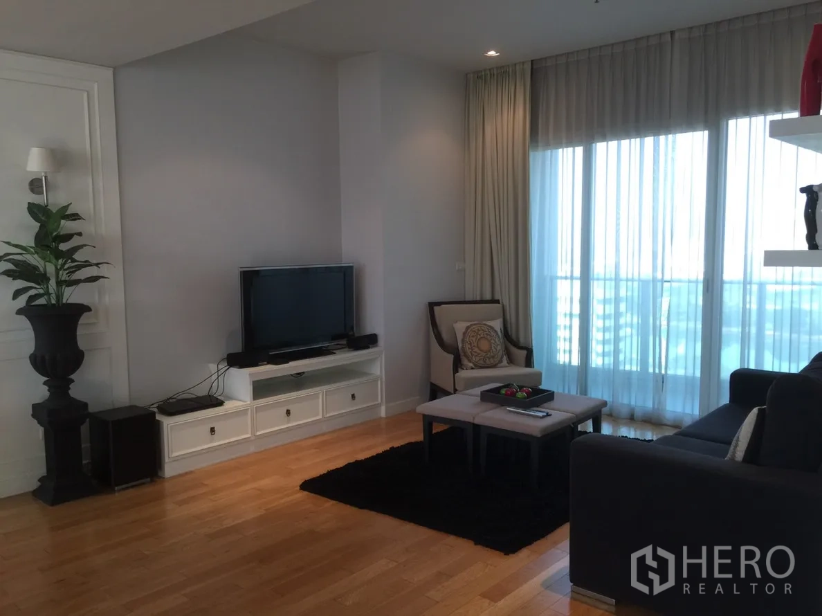 คอนโด ให้เช่าในKhlong Toei, Bangkok - ห้องนั่งเล่นอบอุ่น พร้อมชั้นวางทีวี เก้าอี้เอนกาย และประตูกระจกบานเลื่อนออกระเบียง