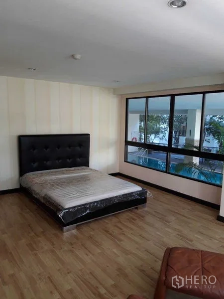 Condominium for sale - Bedroom with wide windows overlooking greenery and pool deck.