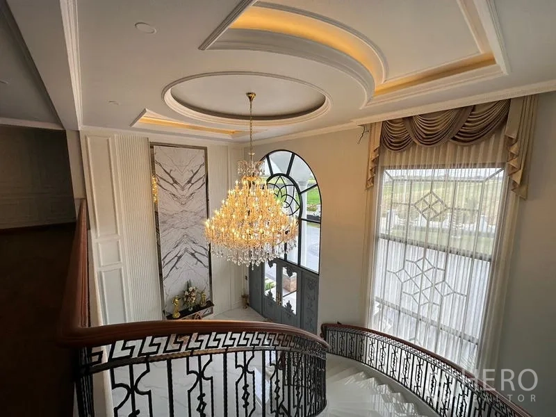 Detached House for sale in Sai Noi, Nonthaburi - Double-height foyer with crystal chandelier, curved staircase and an arched window.