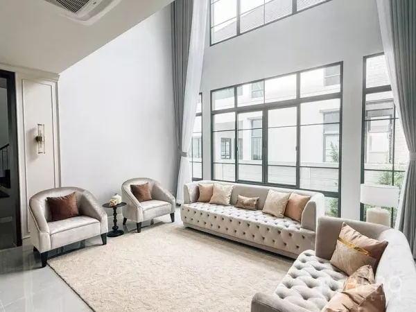 Detached House for rent or sale in Bang Phli, Samut Prakan - Double-height living room with floor-to-ceiling windows, light sofas and long curtains.