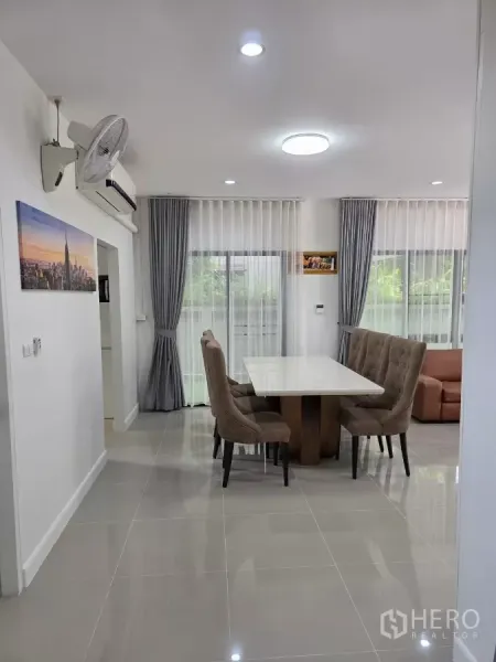 Detached House for rent in Prawet, Bangkok - Bright dining corner with upholstered chairs and sliding glass doors with sheer curtains.