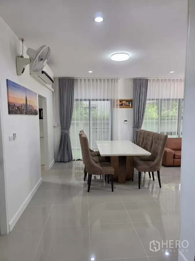 Detached House for rent in Prawet, Bangkok - Bright dining corner with upholstered chairs and sliding glass doors with sheer curtains.