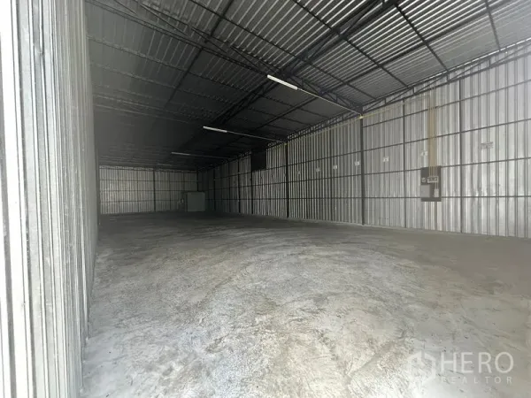 Warehouse for rent in Wang Thonglang, Bangkok - Front view of the warehouse interior showing a large column-free space, ceiling lights, and an electrical panel on the side wall.