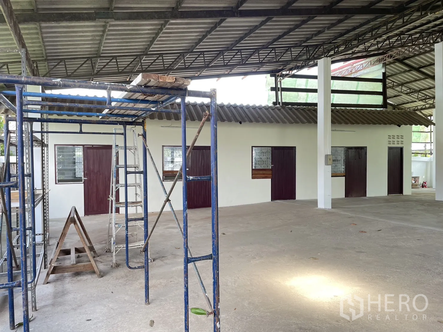 工厂 出租或出售在Pathum Thani - 屋檐下的脚手架与维护区，配多扇木门和钢桁架。