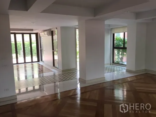 Detached House for rent in Sathon, Bangkok - Bright open-plan living area with large windows, support columns and mixed wood-tile floors