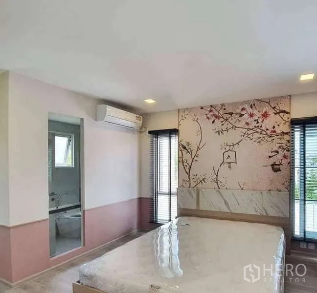 Detached House for rent in Prawet, Bangkok - Master bedroom with floral accent wall, ensuite doorway and tall windows.