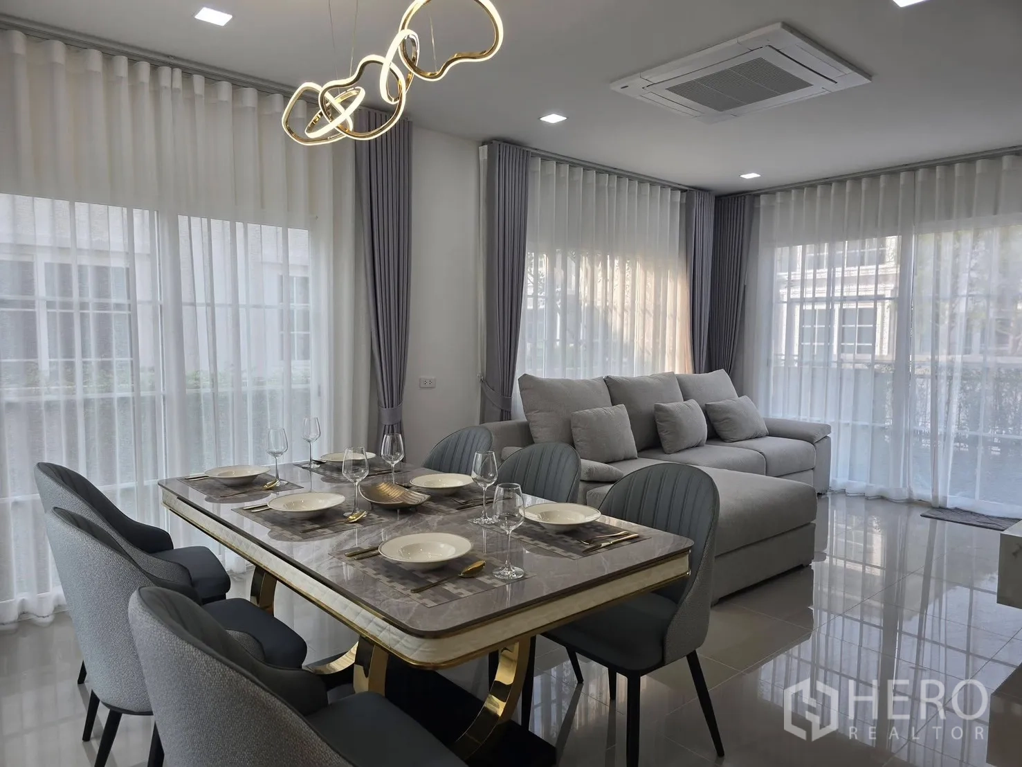 บ้านแฝด for rent in Mueang Samut Prakan, Samut Prakan - โถงนั่งเล่นและรับประทานอาหารแบบโอเพ่น มีโต๊ะหินอ่อน โคมไฟดีไซน์สีทอง และหน้าต่างสูงจรดเพดาน