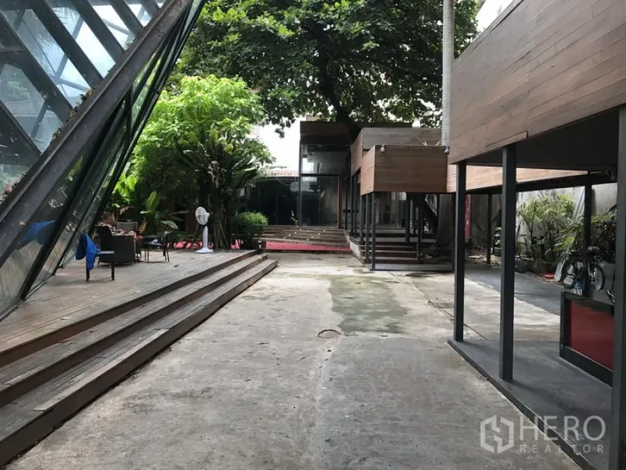 零售空间 出租在Bang Khae, Bangkok - 带木质平台的景观庭院，玻璃亭楼与遮荫休息区。