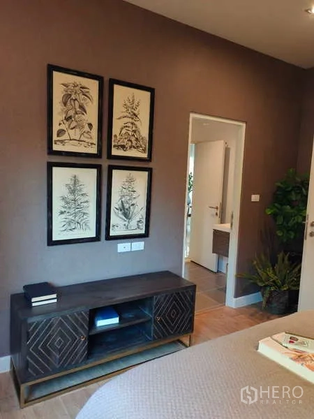 Detached House for rent in Bang Phli, Samut Prakan - Bedroom corner with TV console, botanical wall art and door to bathroom.