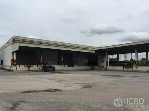 货栈 出租在Pathum Thani - 仓库外立面配有带雨棚装卸月台，车道宽阔，便于叉车与卡车进出。