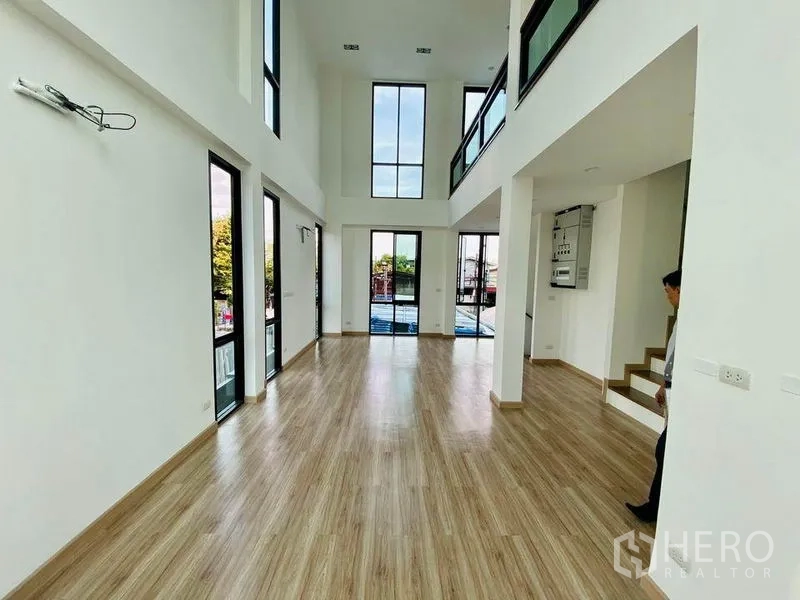 Home Office for sale in Wang Thonglang, Bangkok - Bright double-height hall with floor-to-ceiling windows, mezzanine walkway and wood flooring in a Wang Thonglang home office.