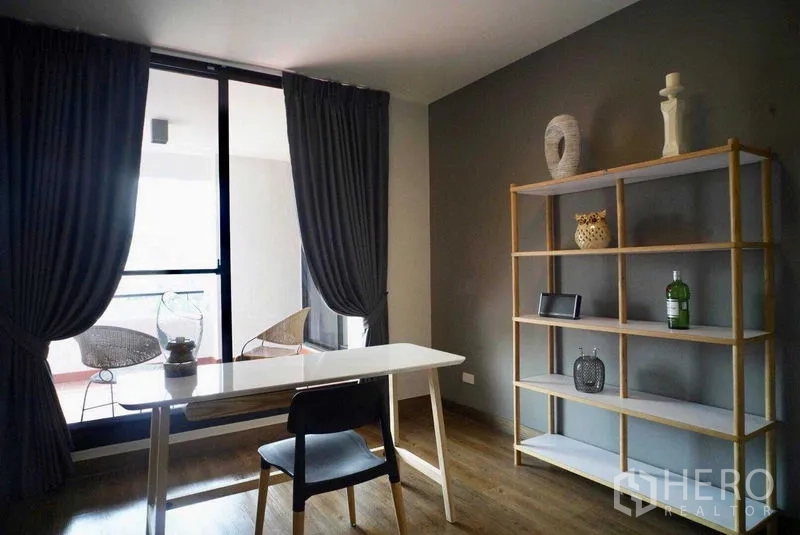 Condominium for rent in Watthana, Bangkok - Home office nook with white desk, shelving and sliding doors to the balcony.