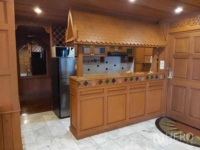 Condominium for rent in Samphanthawong, Bangkok - Thai‑style kitchen with wooden cabinets, tiled counter, and stainless refrigerator.