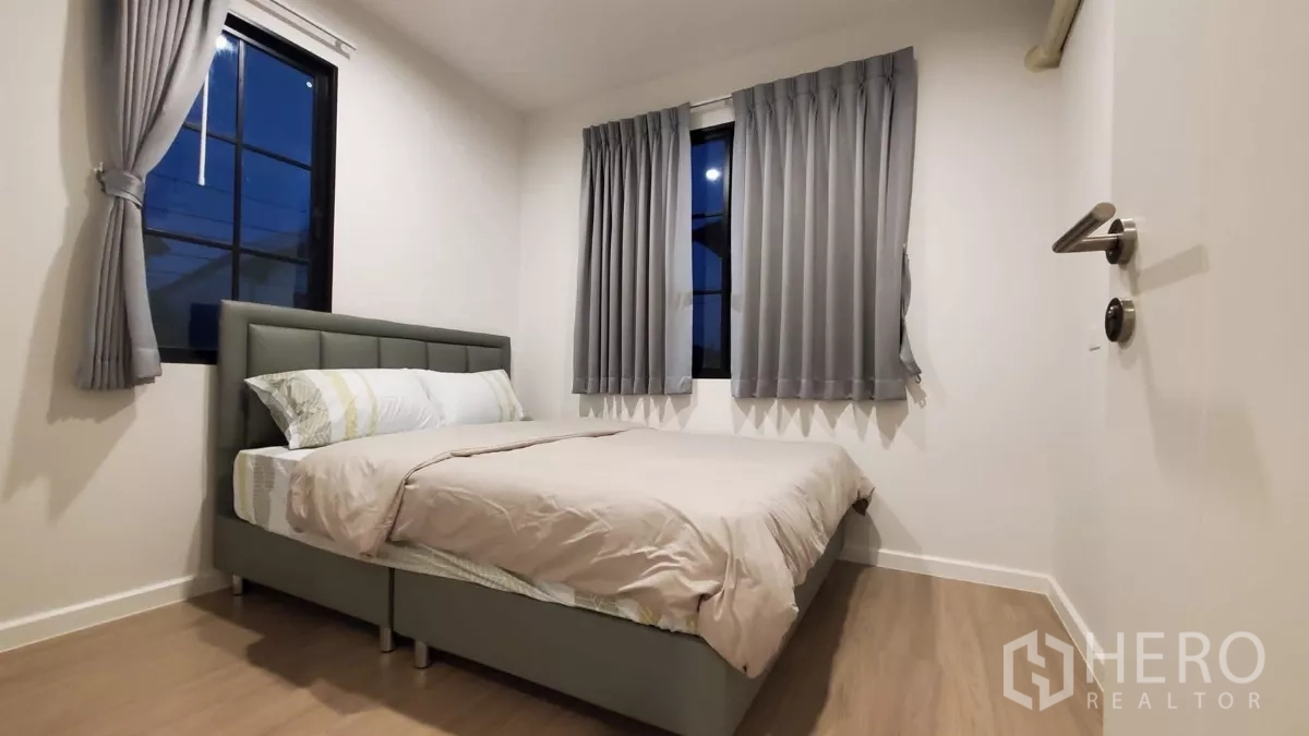 บ้าน ให้เช่าในLat Krabang, Bangkok - ห้องนอนแขก เตียงคู่ ผ้าม่านสีเทา และหน้าต่างมุมห้องในยามค่ำ