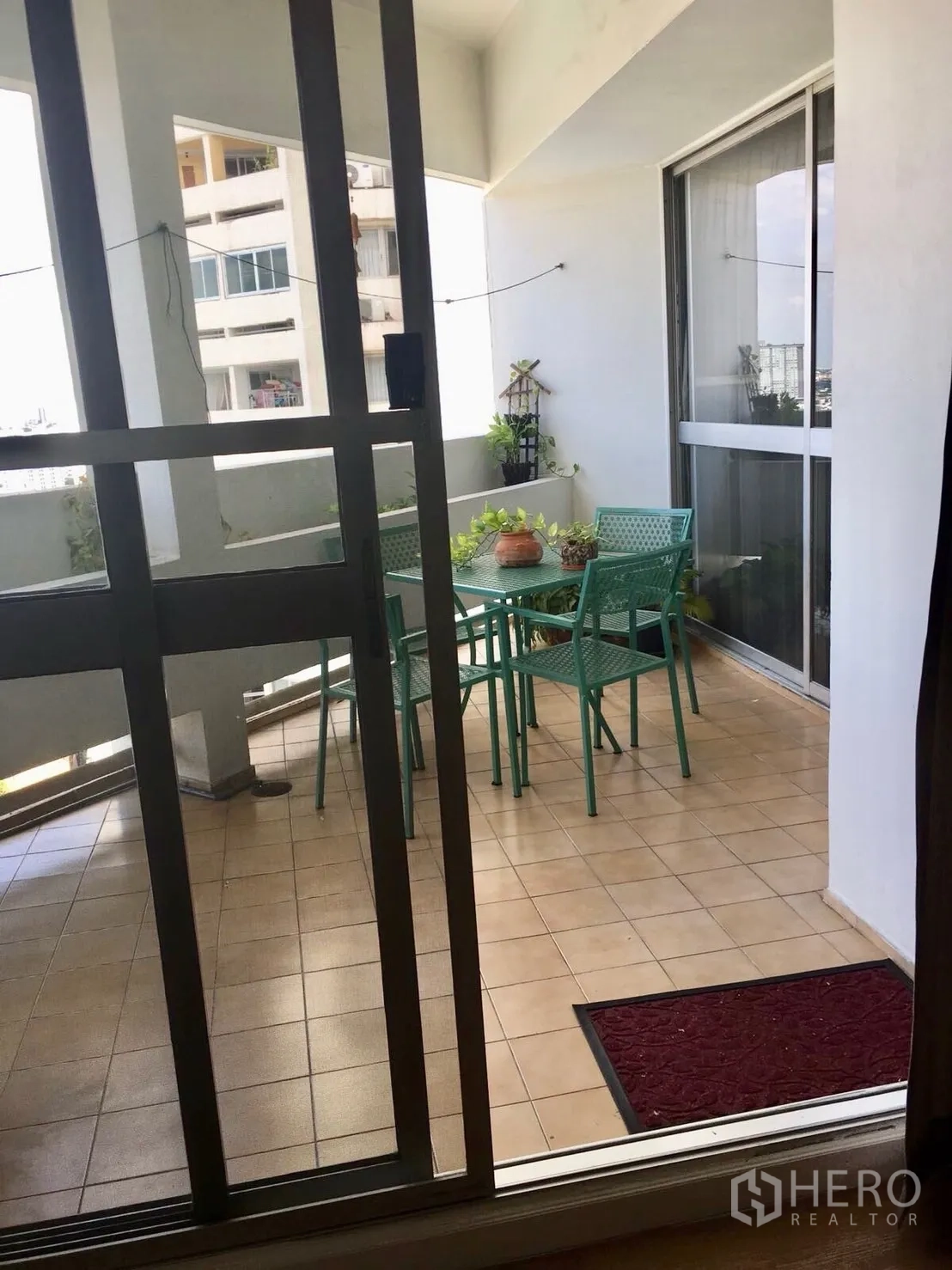 公寓 for rent in Watthana, Bangkok - 透过推拉门可见带顶阳台与绿色户外桌椅。