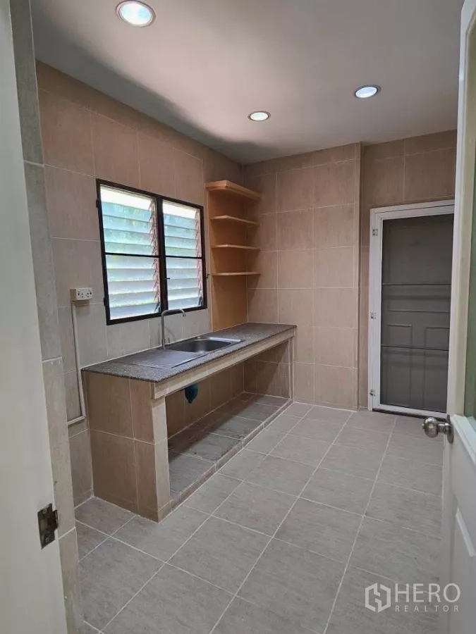 独立式住宅 出租或出售在Mueang Nonthaburi, Nonthaburi - 独立泰式厨房，长操作台、水槽、搁架与后门。