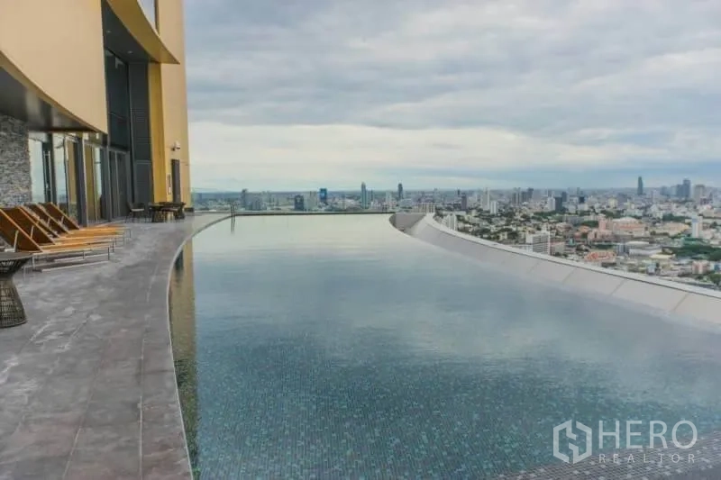 Condominium for rent or sale in Khlong Toei, Bangkok - Rooftop infinity pool with sun loungers and panoramic Bangkok skyline views.