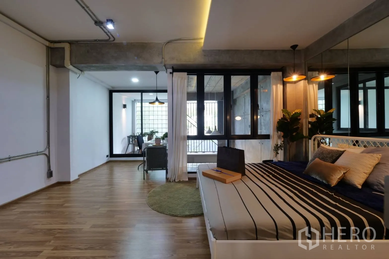 Townhouse for rent in Khlong Toei, Bangkok - Studio-style bedroom with striped bedding, mirrored wall and glass-walled study nook.