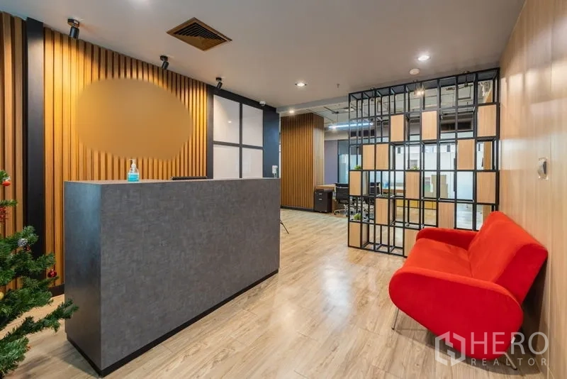 Office Space for rent - Reception area with minimalist counter, red sofa, and slatted wood feature walls.