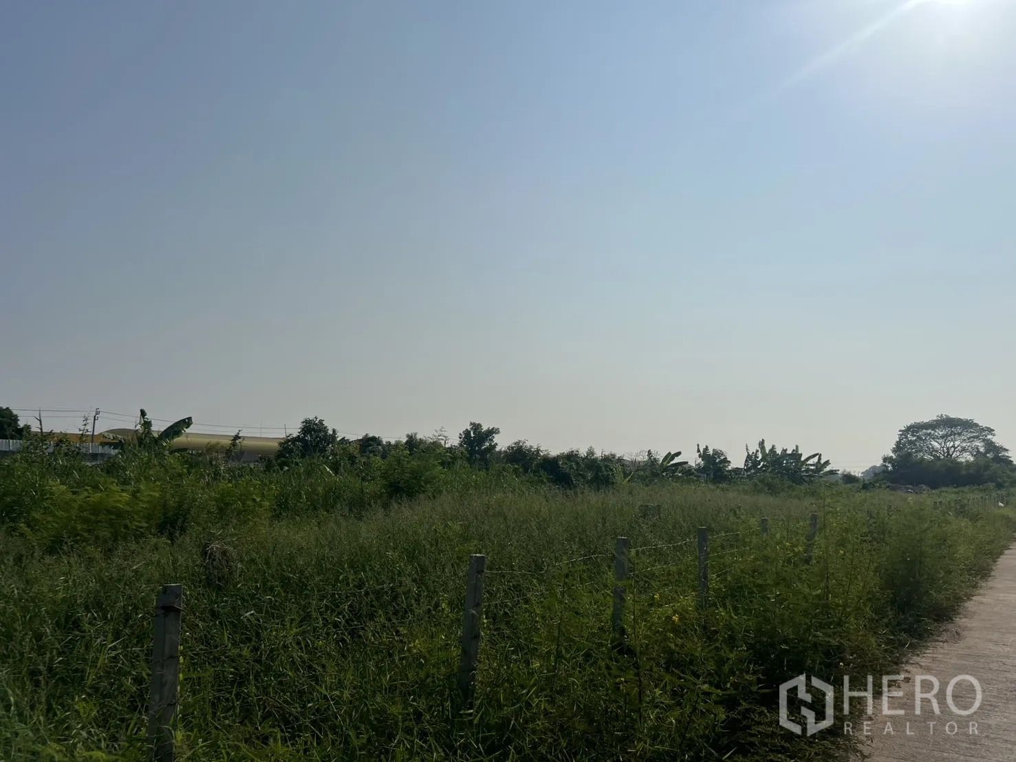 Land for sale in Lat Krabang, Bangkok - Long boundary line of the plot beside a small road and open sky.