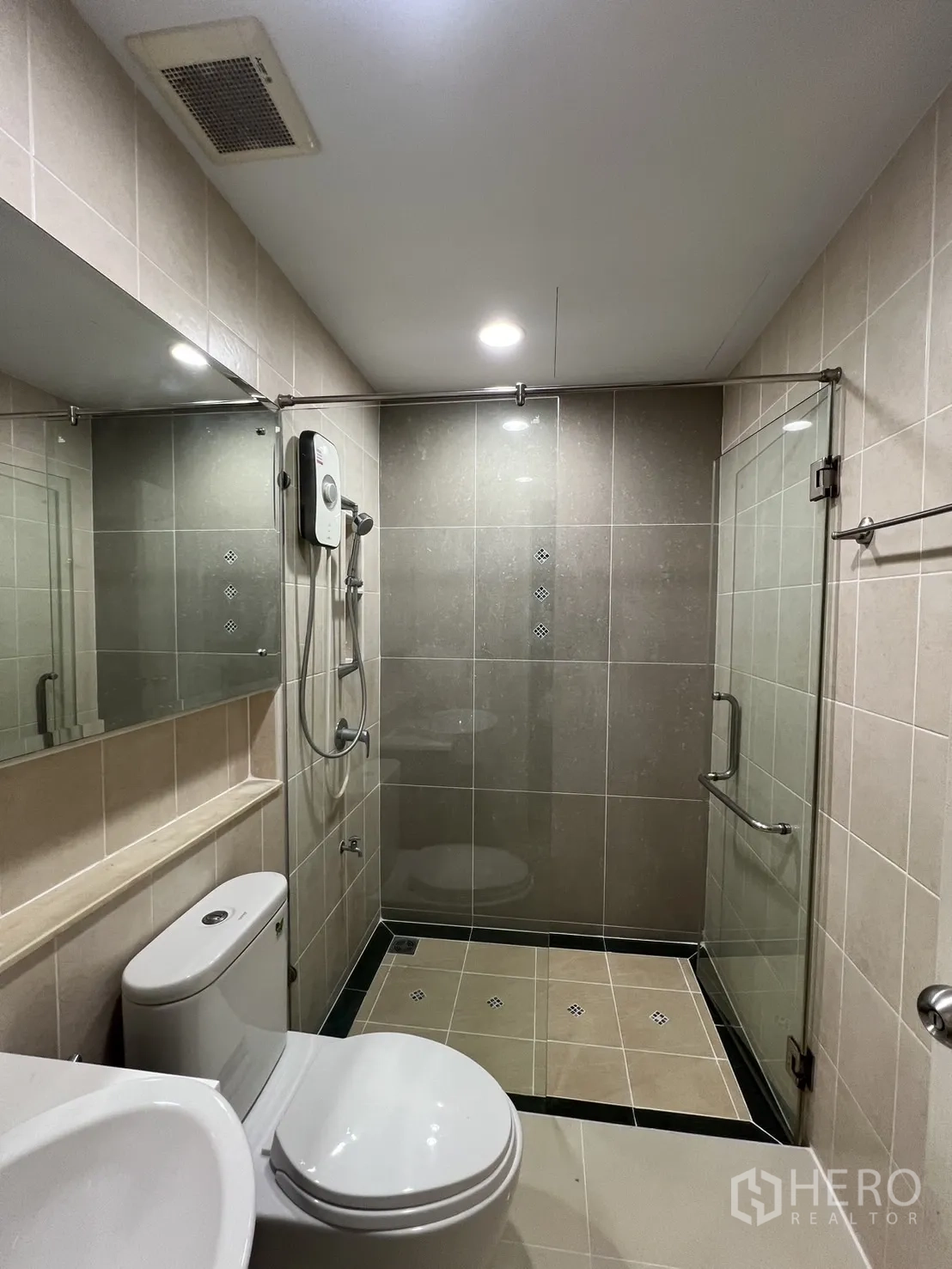Townhouse for rent in Wang Thonglang, Bangkok - Bathroom with glass shower, water heater and neutral tiles.