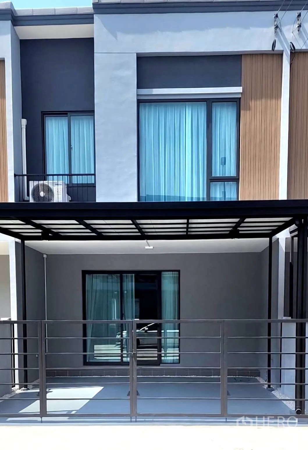 Townhouse for rent in Bang Phli, Samut Prakan - Townhouse facade with covered carport and sliding glass doors.