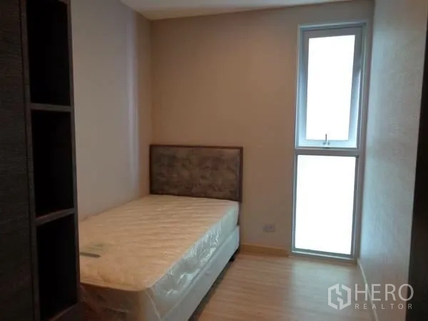 公寓 出租在Watthana, Bangkok - 次卧配单人床，浅色木地板与高窄窗。