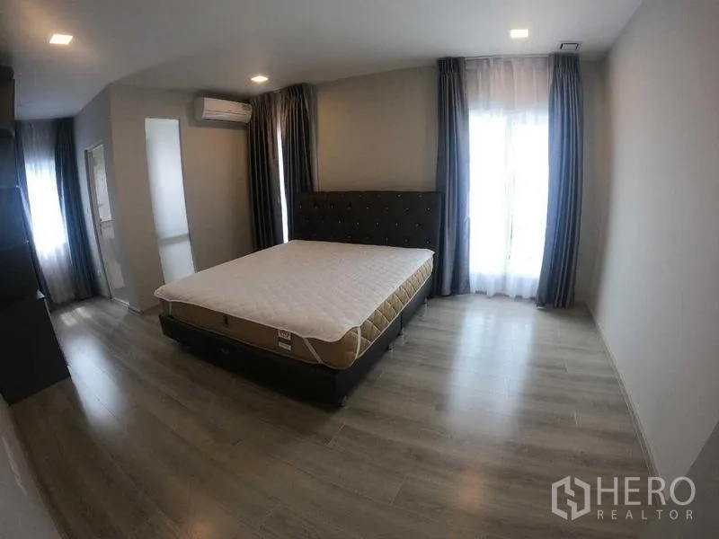 Townhouse for rent - Master bedroom with bed, big windows, curtains, and air conditioning unit.