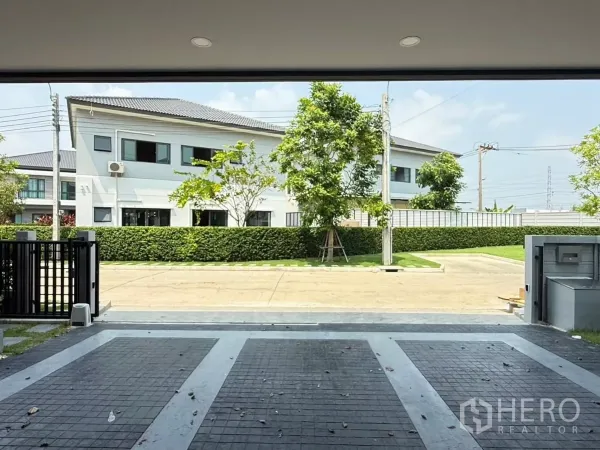 Detached House for rent in Bang Phli, Samut Prakan - Open view from the covered carport toward a quiet internal road and trimmed hedge with no opposite house.