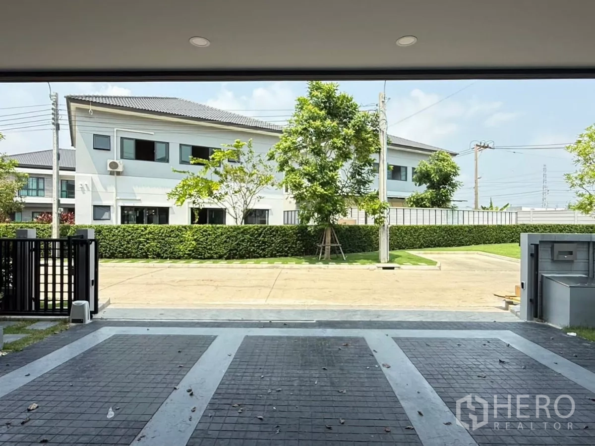 Detached House for rent in Bang Phli, Samut Prakan - Open view from the covered carport toward a quiet internal road and trimmed hedge with no opposite house.