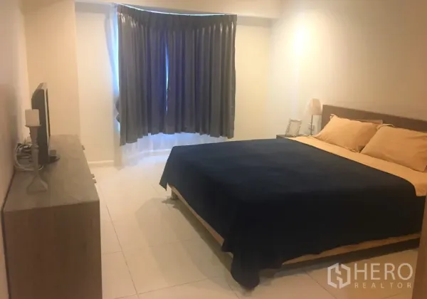 Condominium for rent in Watthana, Bangkok - Master bedroom with king bed, dresser and TV, and a curtained bay window.