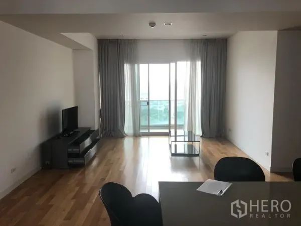 คอนโด ให้เช่าในKhlong Toei, Bangkok - ห้องนั่งเล่นสว่าง พื้นไม้ ทีวีและประตูระเบียงพร้อมผ้าม่าน ในคอนโดเขตคลองเตย