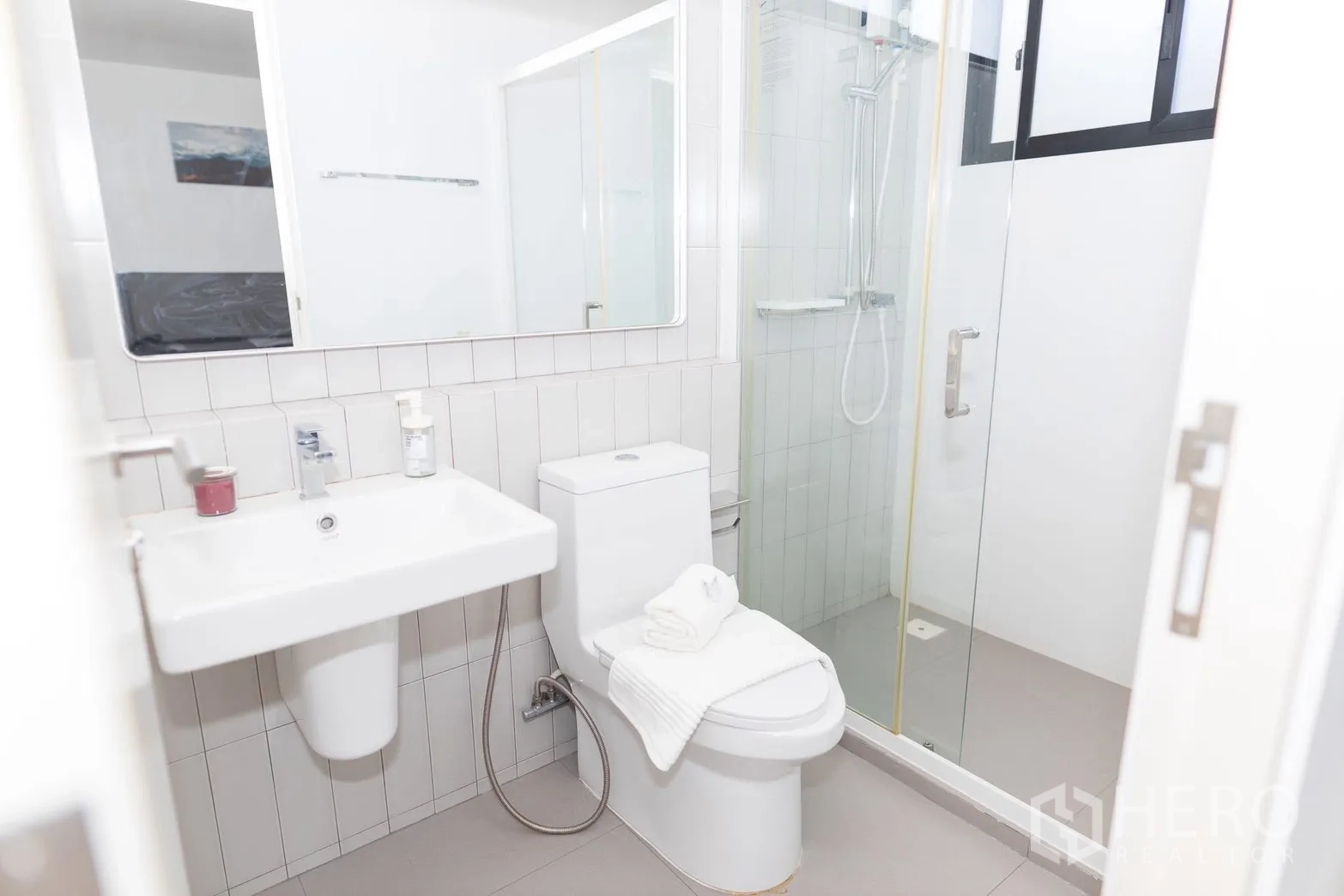 Townhouse for rent in Bang Phli, Samut Prakan - Clean bathroom with glass-enclosed shower, toilet, and wall mirror.