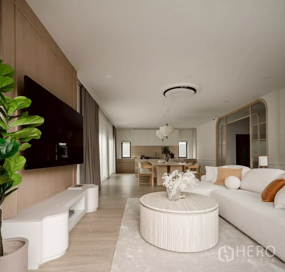 Detached House for rent in Bang Phli, Samut Prakan - Open-plan living room with TV wall, round coffee table, light wood floors and view to the dining kitchen