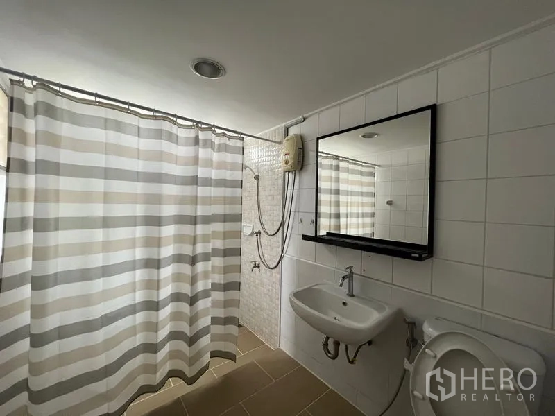 Detached House for rent in Saphan Sung, Bangkok - Bathroom with striped shower curtain, water heater, sink and mirror.