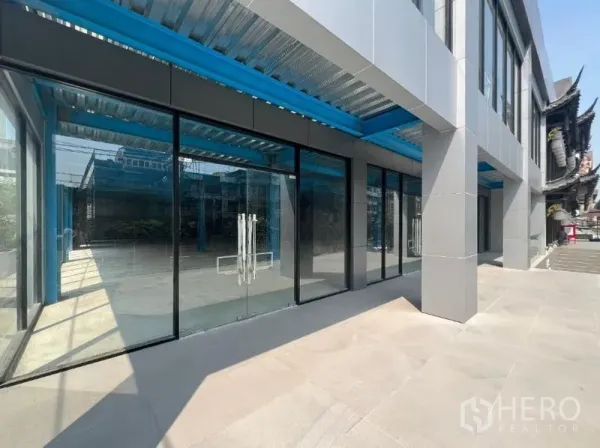 零售空间 出租在Huai Khwang, Bangkok - 一层玻璃店面，双开玻璃门，蓝色钢结构雨棚，外观现代。