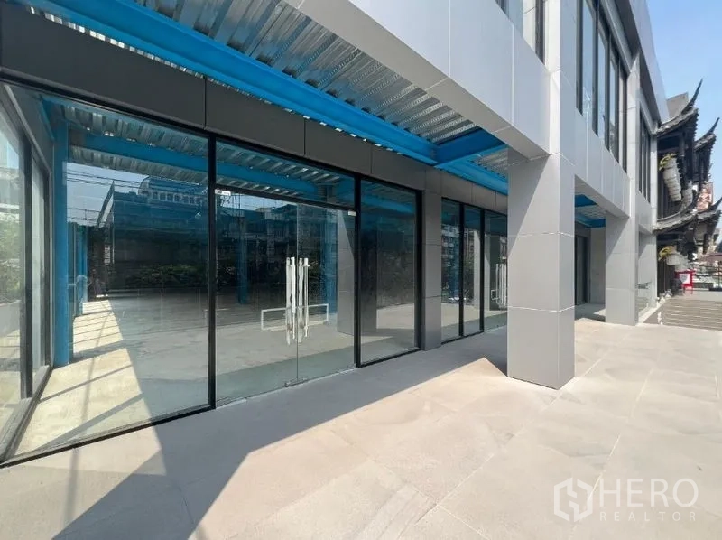 零售空间 出租在Huai Khwang, Bangkok - 一层玻璃店面，双开玻璃门，蓝色钢结构雨棚，外观现代。
