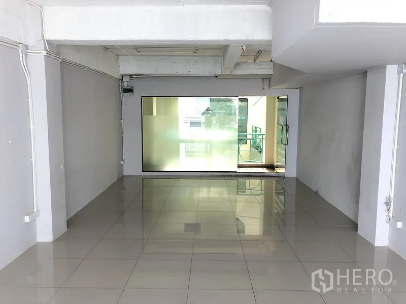 Office Space for rent in Khlong Toei, Bangkok - Open-plan office interior with shiny tiled flooring, frosted glass panel and doorway to a balcony corridor.