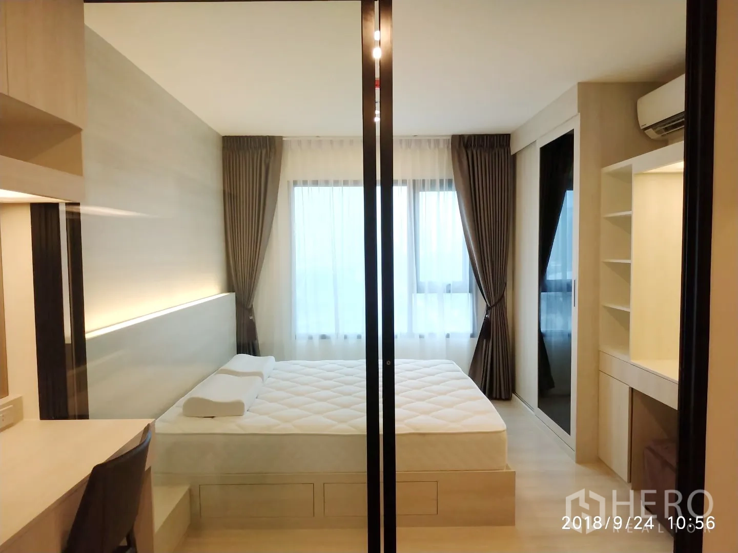 Condominium for rent in Huai Khwang, Bangkok - Bright 1-bedroom with sliding glass partition, queen bed, built-in desk and full-height curtained windows.